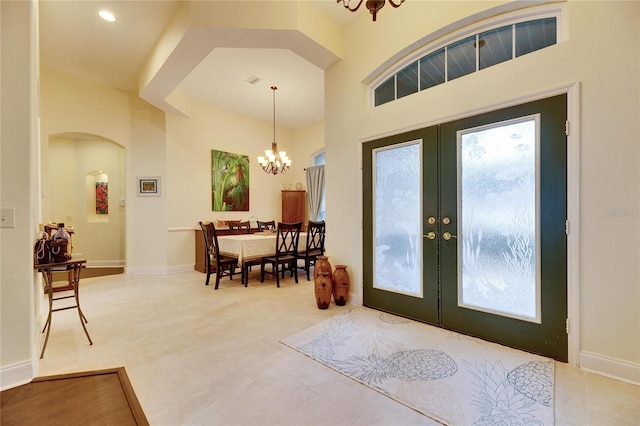 tiled entryway with french doors and an inviting chandelier