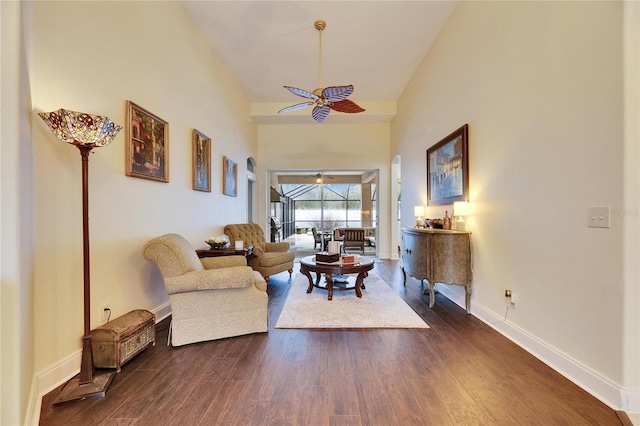 living room featuring ceiling fan, a towering ceiling, and dark hardwood / wood-style flooring