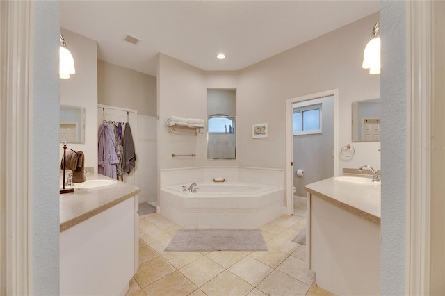 bathroom featuring tile patterned flooring, a relaxing tiled tub, and vanity