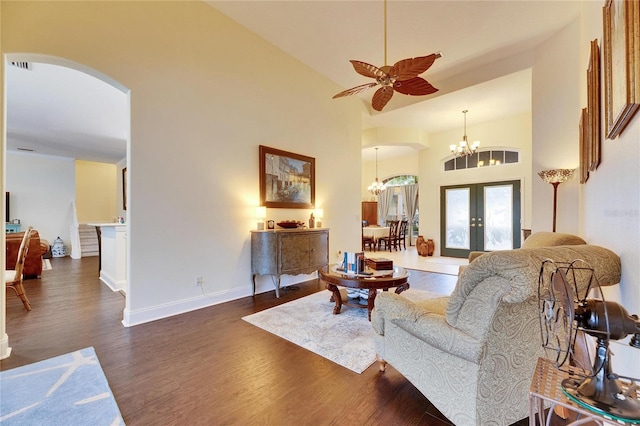 living room with ceiling fan with notable chandelier, dark wood-type flooring, lofted ceiling, and french doors