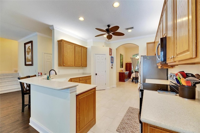 kitchen with stainless steel appliances, sink, ornamental molding, kitchen peninsula, and a breakfast bar