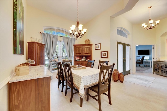 dining space with a high ceiling, french doors, and a notable chandelier