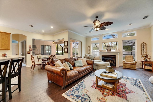 living room featuring ceiling fan, ornamental molding, and dark hardwood / wood-style flooring