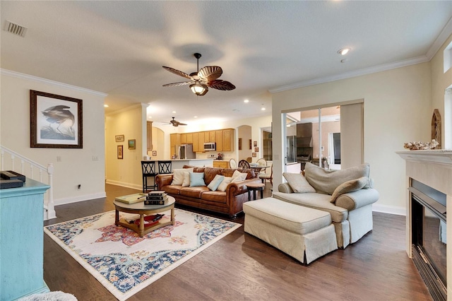 living room with crown molding, dark hardwood / wood-style floors, and ceiling fan