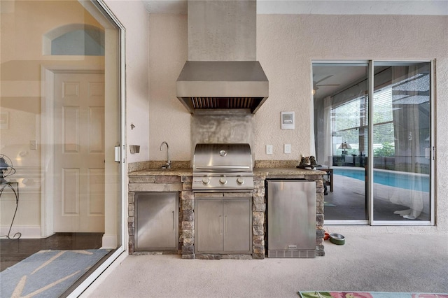 kitchen with sink, carpet flooring, wall chimney range hood, and stainless steel refrigerator