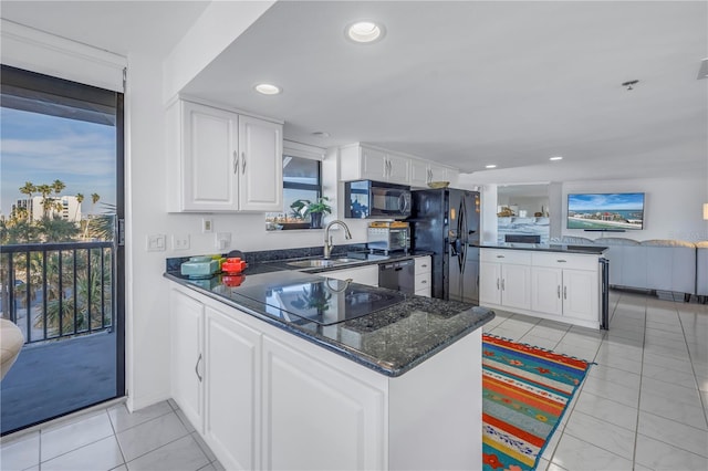 kitchen with sink, light tile patterned floors, kitchen peninsula, white cabinets, and black appliances