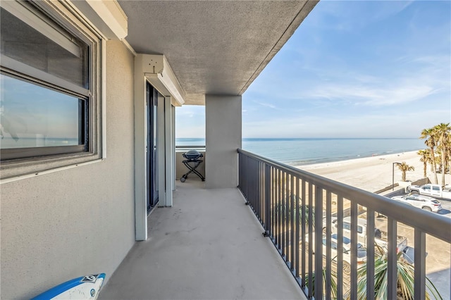 balcony featuring a view of the beach and a water view