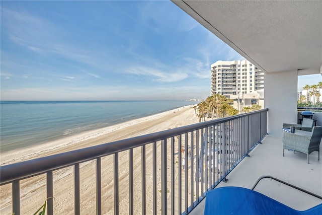 balcony with a water view and a view of the beach