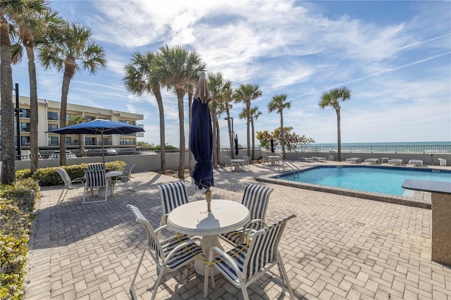 view of pool featuring a patio and a water view