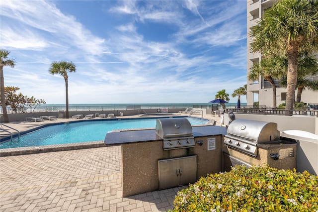 view of swimming pool with a water view, area for grilling, grilling area, and a patio