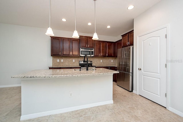 kitchen featuring light stone counters, tasteful backsplash, hanging light fixtures, an island with sink, and stainless steel appliances