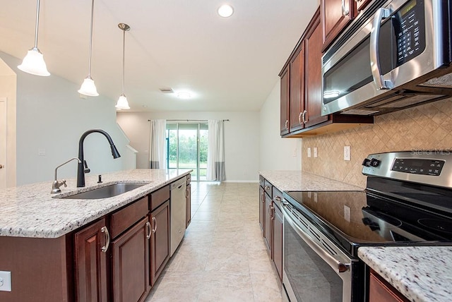 kitchen with pendant lighting, sink, a kitchen island with sink, light stone counters, and stainless steel appliances