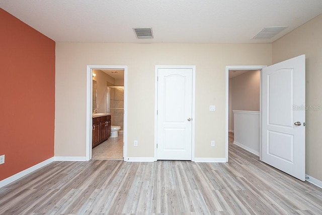 unfurnished bedroom with light hardwood / wood-style floors, a closet, and ensuite bathroom