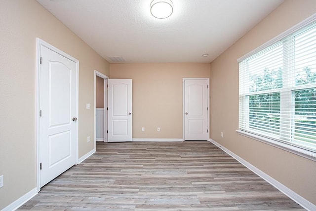 unfurnished bedroom featuring multiple windows and light hardwood / wood-style flooring