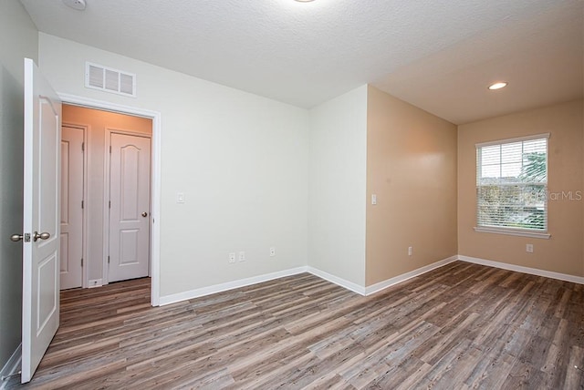 unfurnished room with dark hardwood / wood-style floors and a textured ceiling