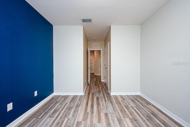 unfurnished room featuring light wood-type flooring and a textured ceiling