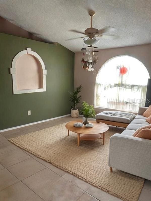 living room featuring ceiling fan, tile patterned flooring, and a textured ceiling