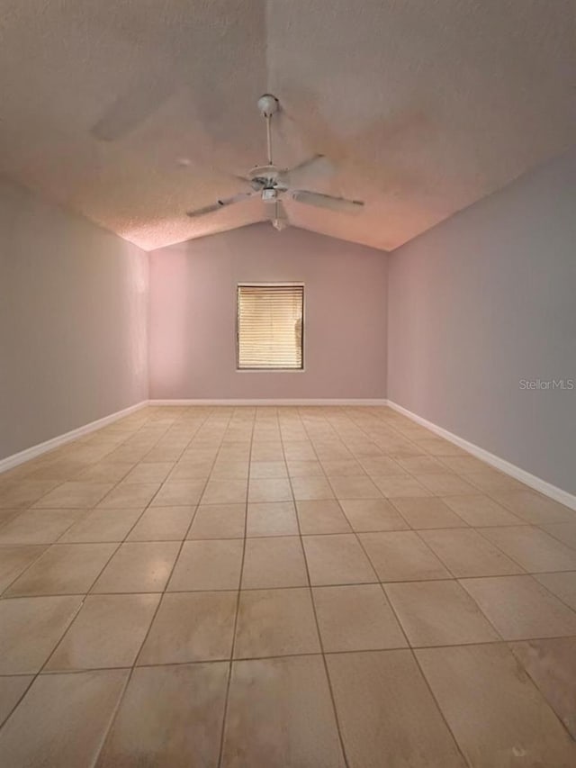 unfurnished room featuring ceiling fan, lofted ceiling, light tile patterned flooring, and a textured ceiling