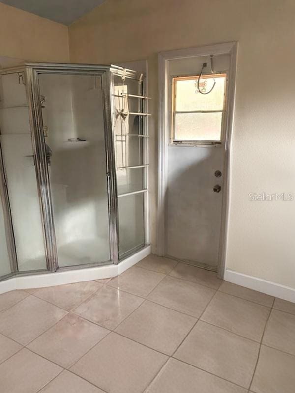 bathroom featuring tile patterned flooring, a shower with shower door, and lofted ceiling