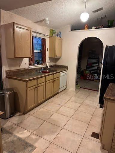 kitchen featuring light tile patterned flooring, dishwasher, sink, and a textured ceiling