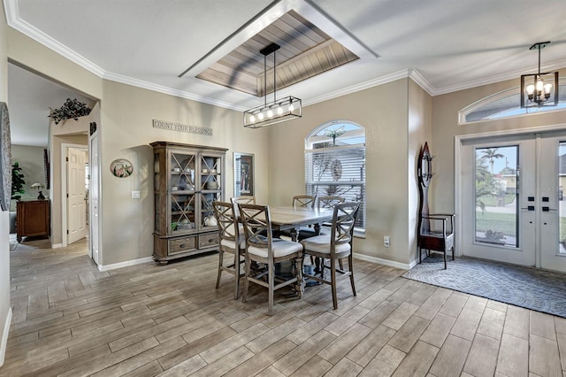 dining area with a chandelier, french doors, a raised ceiling, and ornamental molding