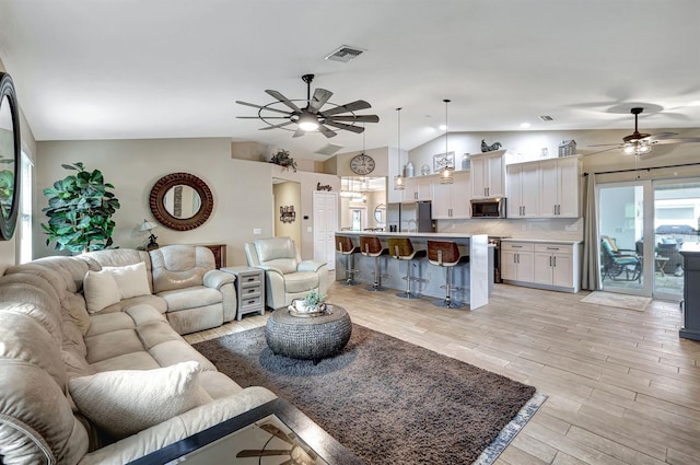 living room featuring light hardwood / wood-style floors, ceiling fan, and vaulted ceiling