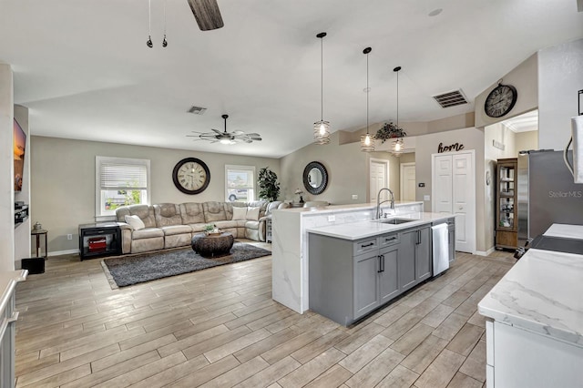 kitchen featuring a kitchen island with sink, sink, decorative light fixtures, stainless steel appliances, and gray cabinets