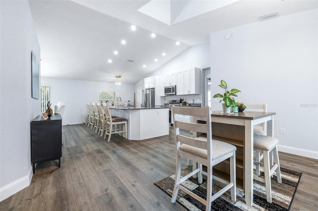 kitchen featuring white cabinetry, a kitchen breakfast bar, kitchen peninsula, stainless steel appliances, and hardwood / wood-style floors