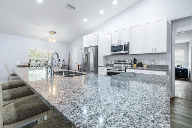 kitchen with a large island with sink, appliances with stainless steel finishes, sink, and a kitchen bar