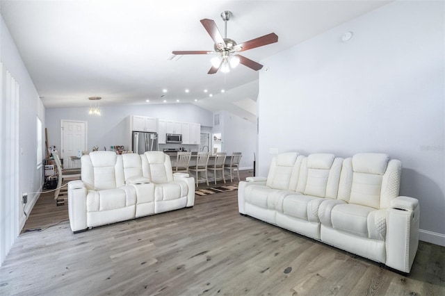 living room featuring vaulted ceiling, ceiling fan, and light wood-type flooring