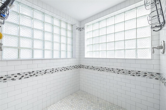 bathroom featuring a tile shower and a healthy amount of sunlight