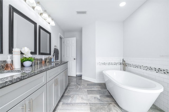 bathroom featuring vanity, a tub to relax in, and tile walls