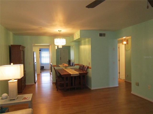 dining space with dark hardwood / wood-style floors and ceiling fan with notable chandelier