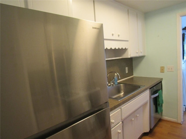 kitchen with sink, hardwood / wood-style flooring, appliances with stainless steel finishes, white cabinetry, and decorative backsplash