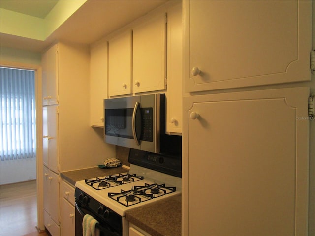 kitchen with white cabinetry, range with gas stovetop, and refrigerator