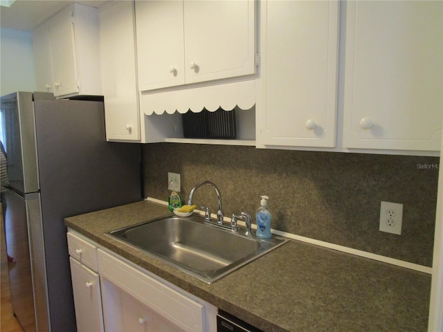 kitchen featuring tasteful backsplash, sink, white cabinets, and stainless steel refrigerator