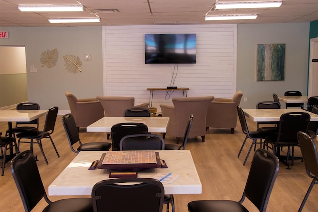 dining space featuring a drop ceiling and light hardwood / wood-style floors