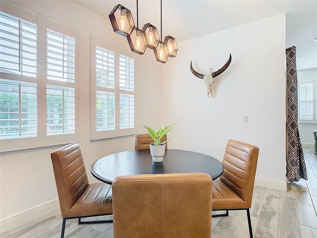 dining room featuring a healthy amount of sunlight, an inviting chandelier, and light wood-type flooring