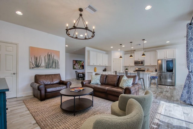 living room featuring a notable chandelier and light wood-type flooring