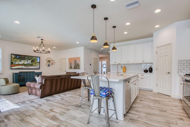 kitchen with sink, a breakfast bar, a kitchen island with sink, white cabinetry, and stainless steel appliances