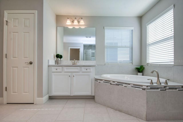 bathroom featuring vanity, a relaxing tiled tub, tile patterned floors, and an inviting chandelier