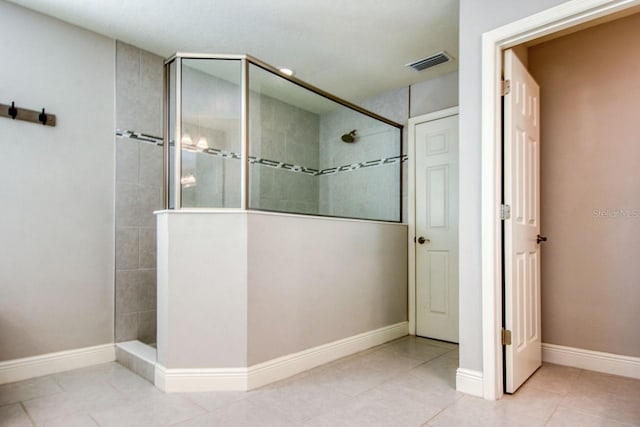 bathroom with tile patterned flooring and a tile shower