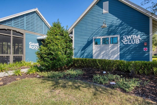 view of side of property with a sunroom and a lawn