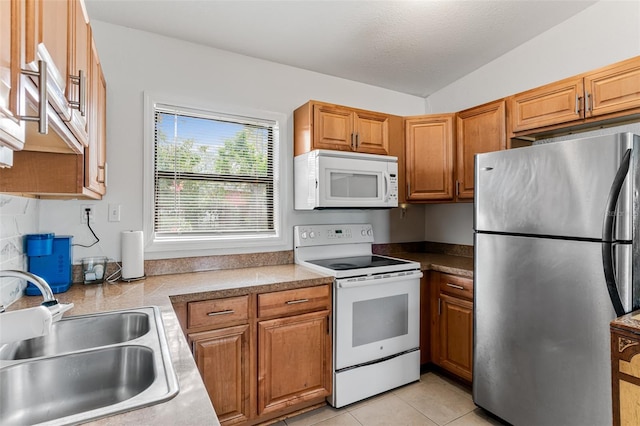 kitchen with sink, white appliances, and light tile patterned floors