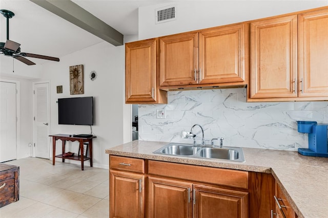 kitchen featuring beamed ceiling, sink, decorative backsplash, light tile patterned floors, and ceiling fan