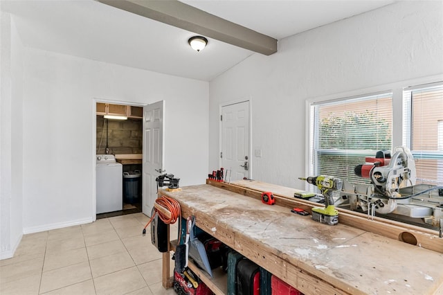 interior space with vaulted ceiling with beams, washer / dryer, a workshop area, and light tile patterned floors