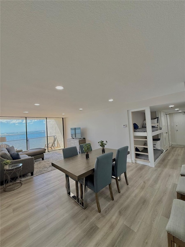 dining area with a wall of windows, a textured ceiling, and light wood-type flooring