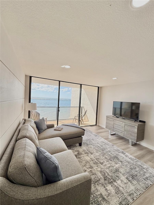 living room with floor to ceiling windows, a textured ceiling, and light hardwood / wood-style floors