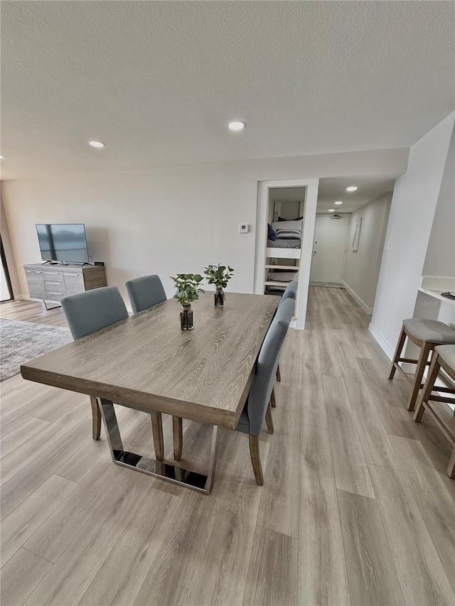 dining space with a textured ceiling and light hardwood / wood-style floors