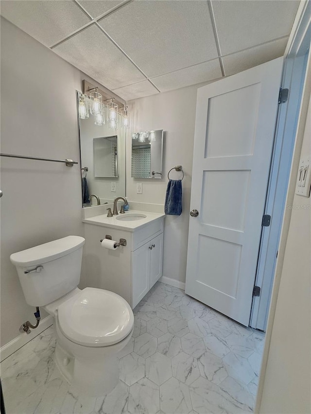 bathroom featuring a drop ceiling, vanity, and toilet